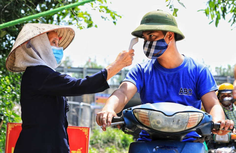 Các bà, các mẹ dù tuổi đã cao vẫn đội nắng tham gia gác chốt kiểm tra y tế giúp chính quyền huyện Đông Anh. (Ảnh: Thành Đạt/TTXVN)