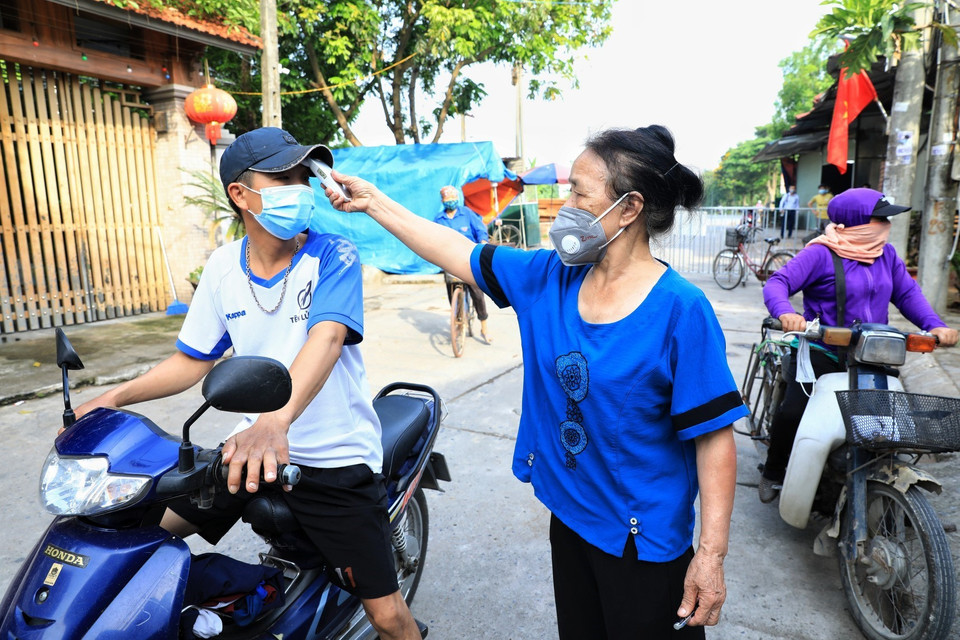 Các bà, các cô thuộc hội Phụ nữ thôn Thù Lỗ, xã Liên Hà, huyện Đông Anh kiểm tra nhiệt độ của người dân mỗi khi ra vào. (Ảnh: Thành Đạt/TTXVN)