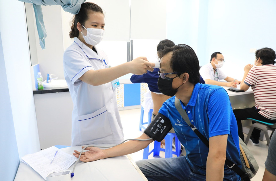 Nhân viên y tế Bệnh viện Bạch Mai kiểm tra thân nhiệt và huyết áp cho các phóng viên trước khi tiêm vaccine. (Ảnh: Thành Đạt/TTXVN)