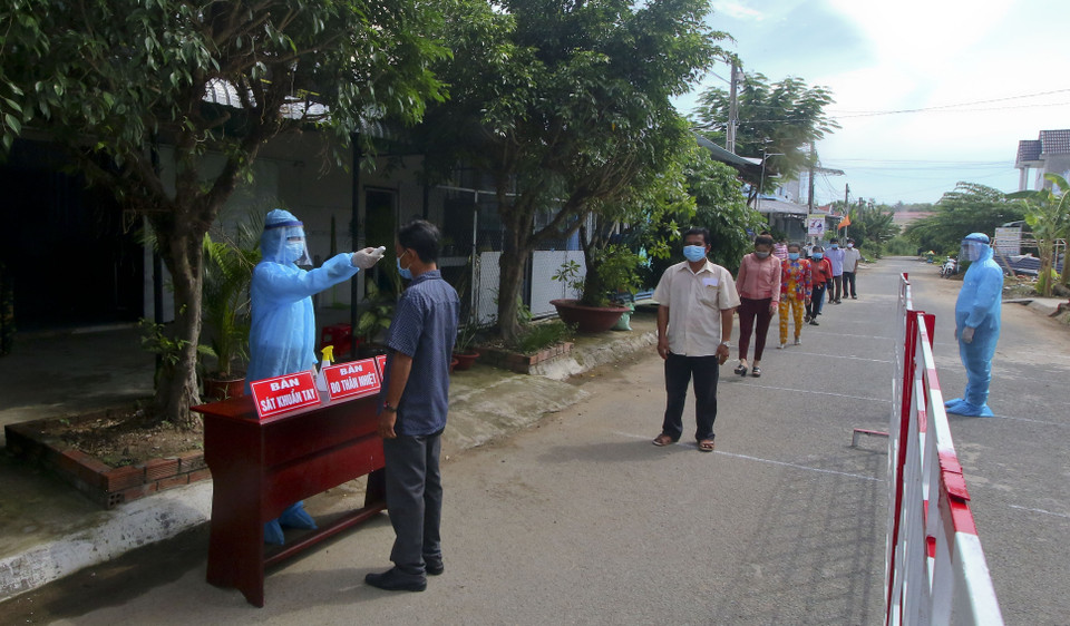 Đo thân nhiệt cho cử tri vùng cách ly y tế trong khu dân cư (khu vực phong tỏa) trước khi tiến hành bỏ phiếu bầu cử. (Ảnh: Duy Khương/TTXVN)
