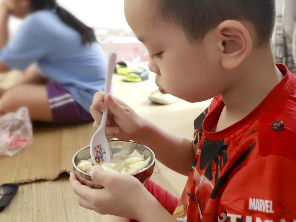 Một bé trai ăn cơm trưa tại khu cách ly. (Ảnh: Hoàng Hùng/TTXVN)
