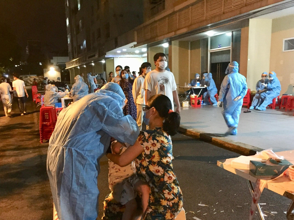 Lấy mẫu xét nghiệm cho toàn bộ cư dân Chung cư Sen Xanh tối 27/5. (Ảnh: Hứa Chung/TTXVN)