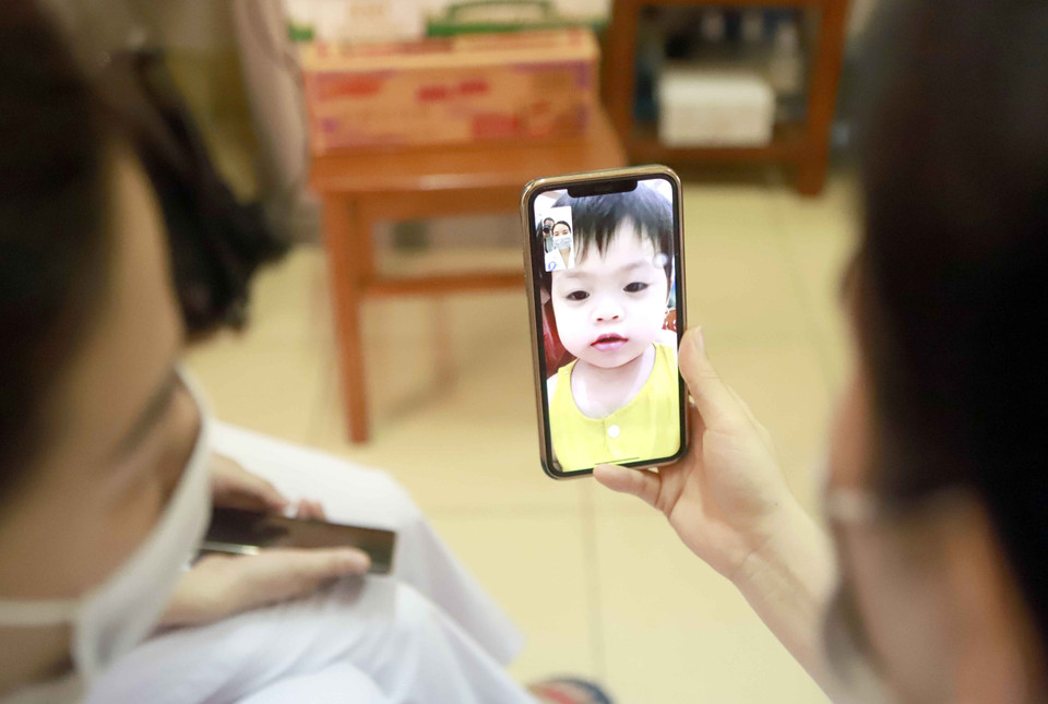Nhân viên Trung tâm kiểm soát bệnh tật tỉnh Vĩnh Phúc trò chuyện với con cho vơi nỗi nhớ gia đình. (Ảnh: Hoàng Hùng/TTXVN)