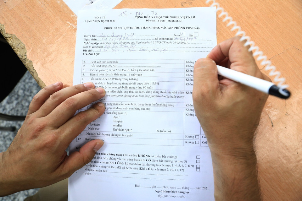 Các phóng viên khai thông tin cá nhân trước khi tiêm vaccine AstraZeneca. (Ảnh: Thành Đạt/TTXVN)