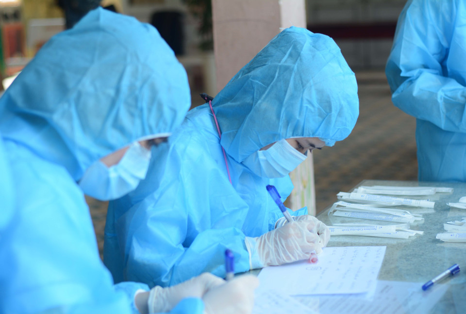 Nhân viên y tế lấy danh sách người đến xét nghiệm COVID-19. (Ảnh: Văn Dũng/TTXVN)