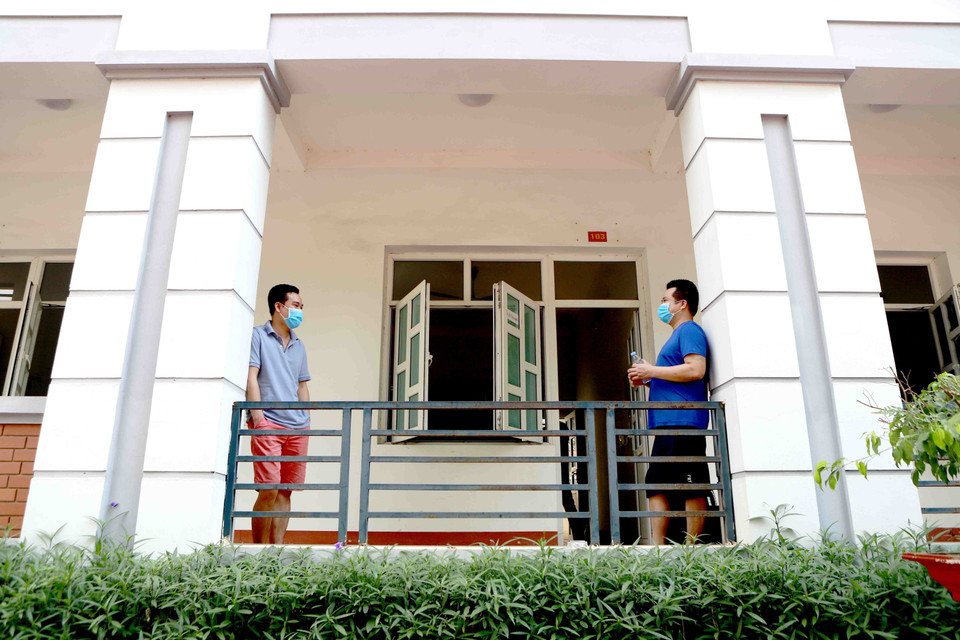 Hai người trò chuyện với nhau tại khu cách ly Trung đoàn 834 giữ đúng khoảng cách theo quy định. (Ảnh: Hoàng Hùng/TTXVN)