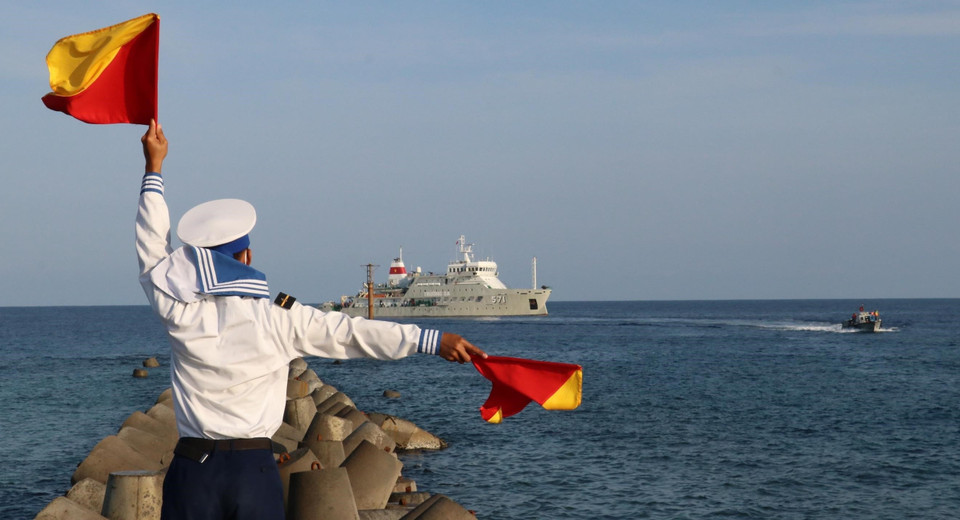 Chiến sỹ đảo Song Tử Tây phất cờ ra hiệu hướng dẫn xuồng máy chở cán bộ, chiến sỹ từ tàu Trường Sa 571 lên thăm đảo Song Tử Tây. (Ảnh: Sỹ Tuyên/TTXVN)