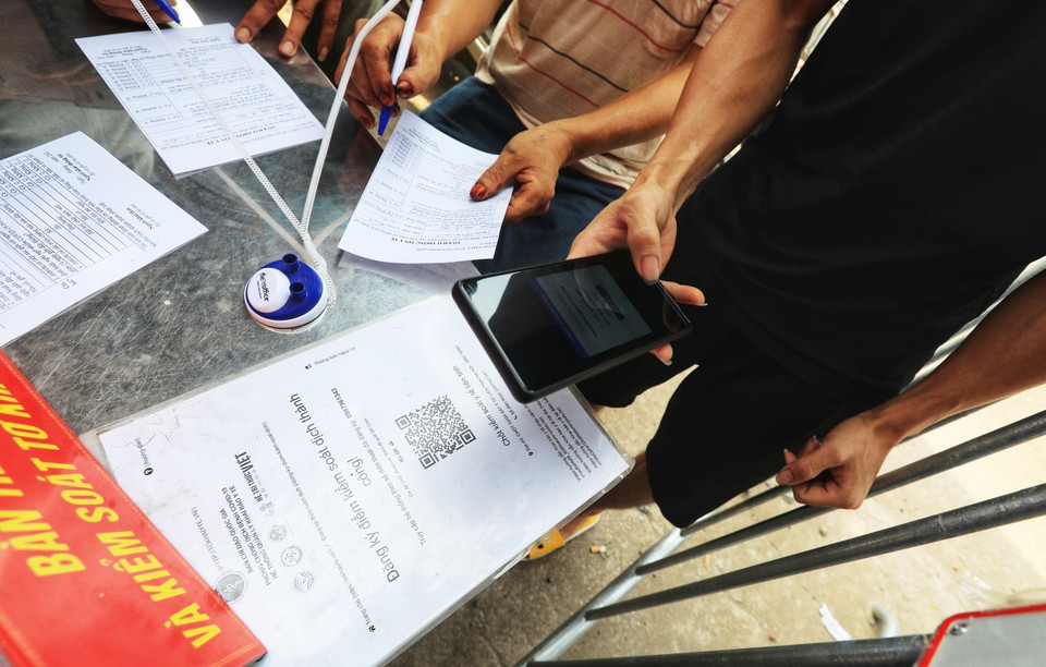 Người dân đi qua chốt kiểm dịch giáp ranh giữa xã Vân Hà, Đông Anh với huyện Từ Sơn, Bắc Ninh phải khai báo y tế bằng cách quét mã QR-code. (Ảnh: Tuấn Anh/TTXVN)