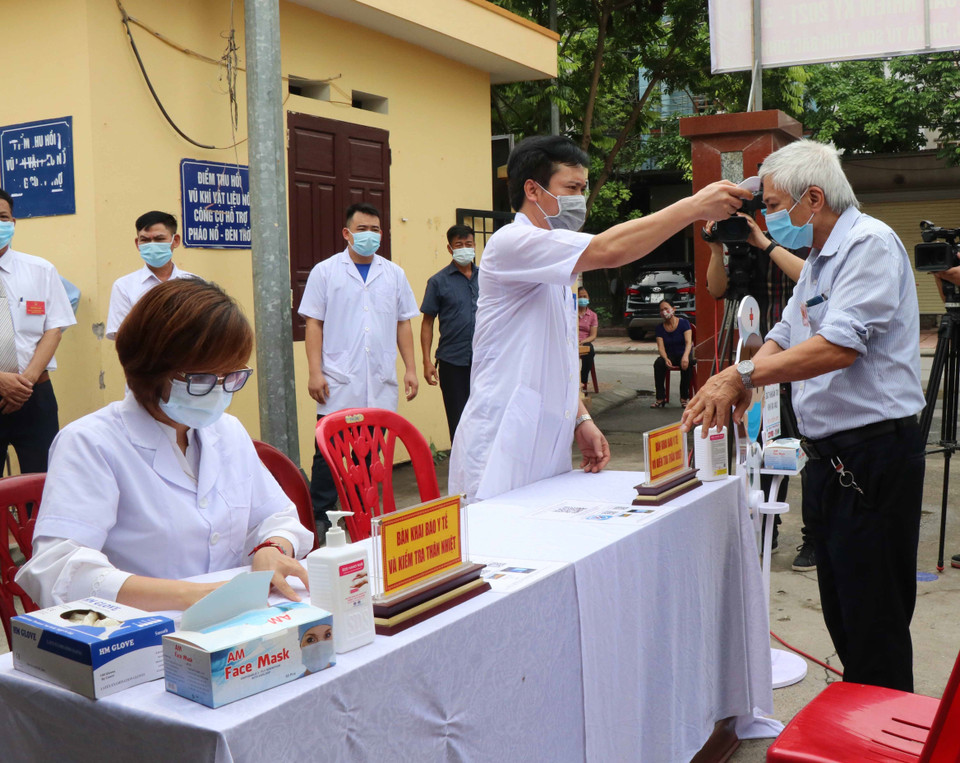 Cử tri được đo thân nhiệt, sát khuẩn tay trước khi vào bầu cử. (Ảnh: Thái Hùng/TTXVN)