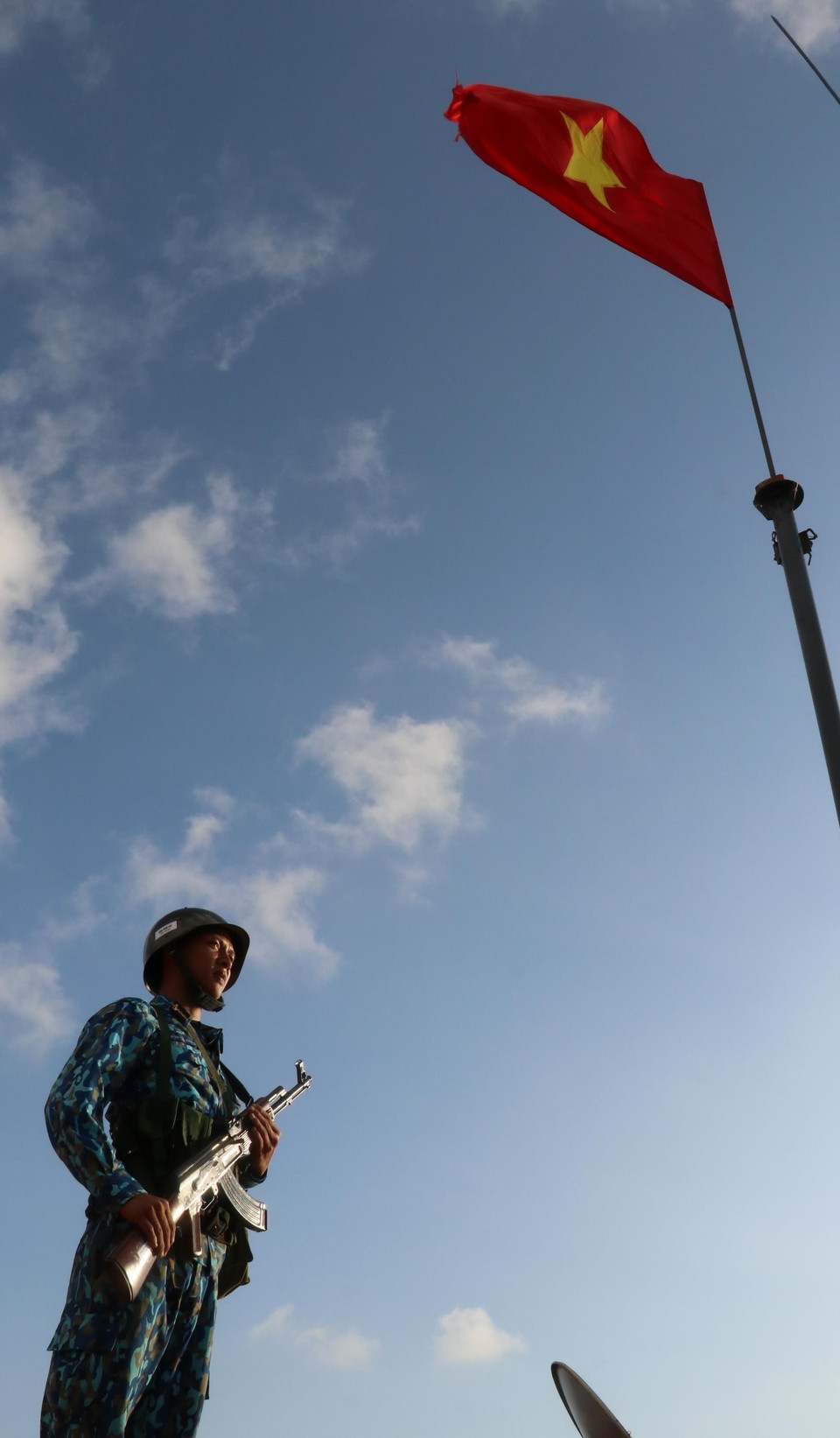 Trung sỹ Đặng Trọng Hiếu - Đảo Thuyền Chài C đứng gác dưới cột cờ Tổ quốc trên nóc đảo. (Ảnh: Sỹ Tuyên/TTXVN)