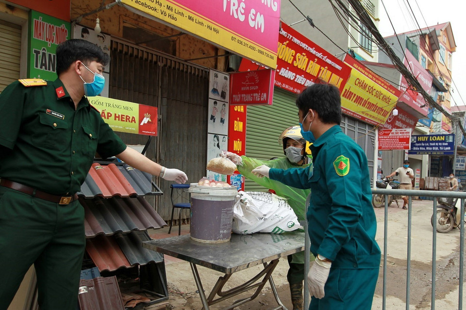 Hàng nhu yếu phẩm được giao nhận gián tiếp đúng quy trình để vào khu cách ly tại thôn Hạ Lôi. (Ảnh: Minh Quyết/TTXVN)