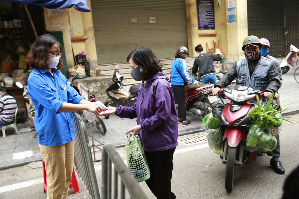 Thanh niên tình nguyện bơm dung dịch sát khuẩn cho nhân dân vào chợ Thanh Hà, phường Đồng Xuân, quận Hoàn Kiếm. (Ảnh: Doãn Tấn/TTXVN)