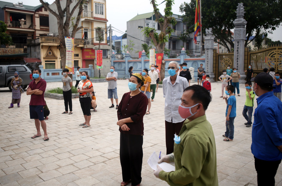 Người dân thôn Hạ Lôi xếp hàng, giữ khoảng cách an toàn để đợi xét nghiệm. (Ảnh: Danh Lam/TTXVN)