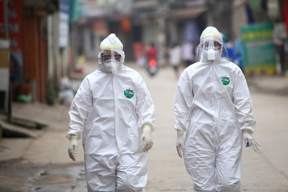 Những nhân viên y tế trong đồng phục bảo hộ thực hiện nhiệm vụ tại thôn Hạ Lôi. (Ảnh: Minh Quyết/TTXVN)