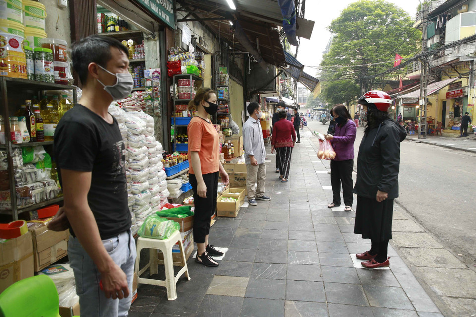 Người dân đứng mua hàng theo vạch sơn được cơ quan chức năng đánh dấu tại phố Nguyễn Thiện Thuật, phường Đồng Xuân, quận Hoàn Kiếm. (Ảnh: Doãn Tấn/TTXVN)