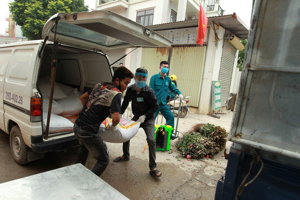 Hàng nhu yếu phẩm được đưa vào thôn Hạ Lôi được khử khuẩn theo đúng quy trình. (Ảnh: Minh Quyết/TTXVN)