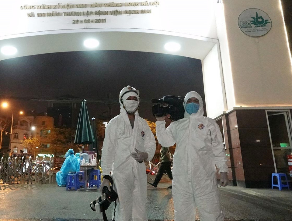 Phóng viên Dương Giang tác nghiệp sự kiện phong tỏa và khử khuẩn Bệnh viện Bạch Mai tối 28/3/2020. (Nguồn: TTXVN)