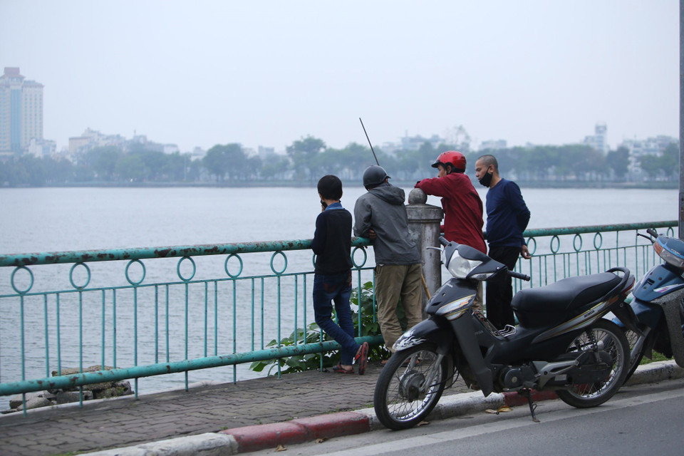 Những người này tụ tập tại đây để câu cá và thỏa mãn sự hiếu kỳ, đeo khẩu trang không đúng cách, không thực hiện đúng cự ly giãn cách 2m trên tuyến đường quanh Hồ Tây. (Ảnh: Anh Tuấn/TTXVN)