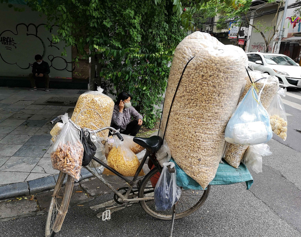 Chiều 12/4, những người bán hàng rong vẫn đi tới nhiều ngõ, phố của Hà Nội để bán hàng tiềm ẩn nguy cơ lây lan dịch bệnh. (Ảnh: Thanh Tùng/TTXVN)