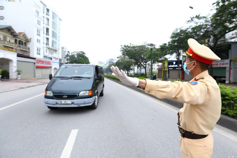 Cảnh sát giao thông hướng dẫn phương tiện dừng xe kiểm soát khi vào nội đô. (Ảnh: Minh Quyết/TTXVN)