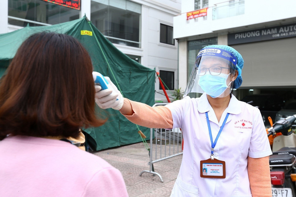 Nhân viên y tế kiểm tra thân nhiệt cho tài xế tại chốt kiểm soát phía Bắc cầu Chương Dương hướng vào nội thành. (Ảnh: Minh Quyết/TTXVN)