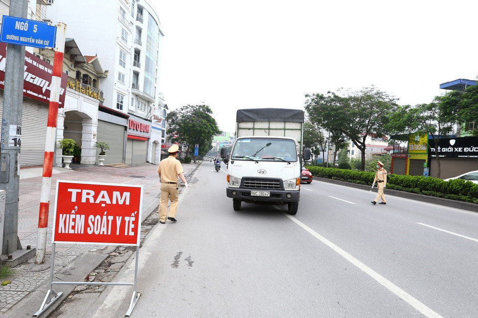 Cảnh sát giao thông hướng dẫn phương tiện dừng xe kiểm soát khi vào nội đô. (Ảnh: Minh Quyết/TTXVN)