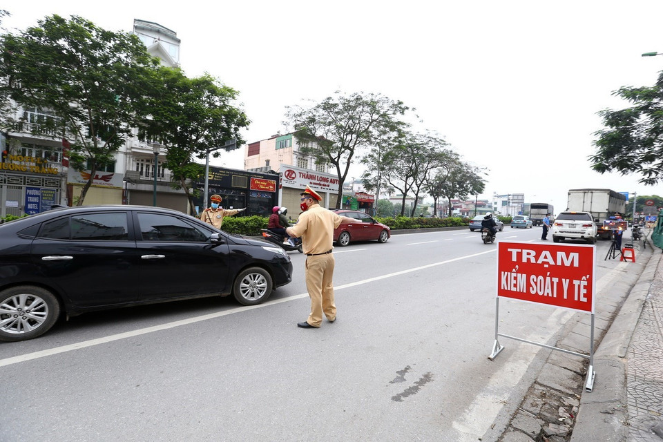 Cảnh sát giao thông hướng dẫn phương tiện dừng xe kiểm soát khi vào nội đô. (Ảnh: Minh Quyết/TTXVN)
