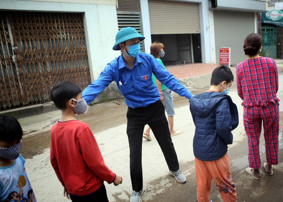 Lực lượng Đoàn Thanh niên của thôn Hạ Lôi hướng dẫn các em nhỏ đứng đúng cự ly chờ xét nghiệm theo quy định. (Ảnh: Danh Lam/TTXVN)