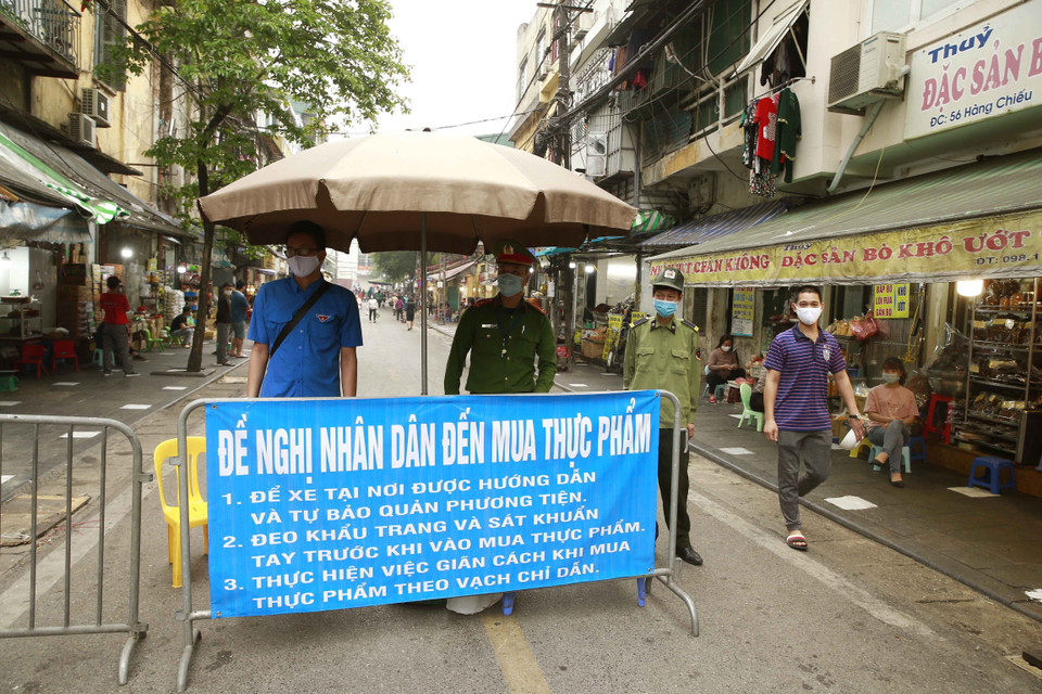 Các lực lượng chức năng làm nhiệm vụ giãn cách xã hội tại phố Nguyễn Thiện Thuật, phường Đồng Xuân, quận Hoàn Kiếm. (Ảnh: Doãn Tấn/TTXVN)