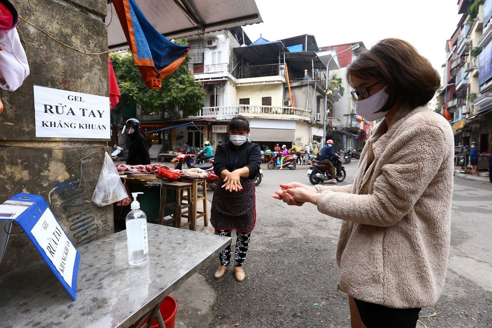  Khu vực cổng chợ có đặt bình sát khuẩn tay, nhắc nhở người dân thực hiện nghiêm các biện pháp về phòng, chống dịch bệnh. (Ảnh: Minh Quyết/TTXVN)