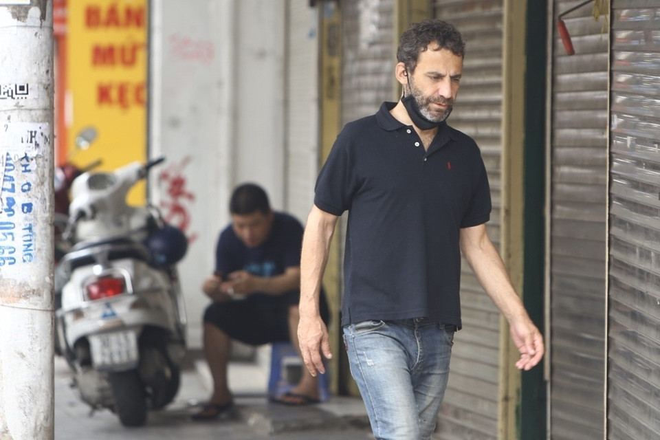 Một người nước ngoài đeo khẩu trang không đúng quy định, theo kiểu đối phó khi di chuyển trên phố Hàng Đường (ảnh chụp trưa 21/4/2020). (Ảnh: Minh Quyết/TTXVN)