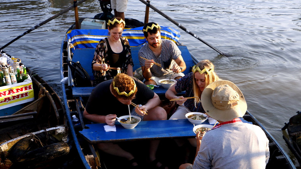 Du khách nước ngoài thưởng thức hủ tiếu, món ăn sáng nổi tiếng ở Chợ nổi Cái Răng. (Ảnh: Thanh Liêm/TTXVN)