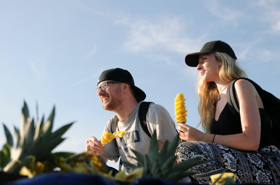 Du khách quốc tế thưởng thức trái dứa (khóm) một loại trái cây đặc trưng tại chợ nổi. (Ảnh: An Hiếu/TTXVN)