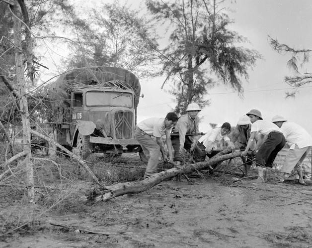 Mặc cho địch đánh phá dọc đường, các đồng chí lái xe bộ đội, cùng công nhân Công ty vận tải hàng hóa Hà Nội nhanh chóng quyết hậu quả, bảo đảm thông đường đưa hàng vào tuyến lửa Khu V an toàn (1971). (Ảnh: Đinh Quang Thành/TTXVN)