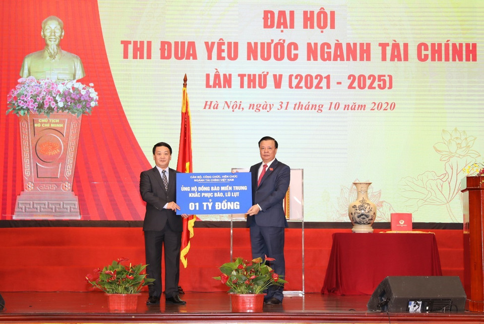 Bộ trưởng Bộ Tài chính Đinh Tiến Dũng trao tượng trưng cho ông Hầu A Lềnh, Phó Chủ tịch, Tổng Thư ký Ủy ban Trung ương Mặt trận Tổ quốc Việt Nam số tiền 1 tỷ đồng của cán bộ, công chức, viên chức ngành Tài chính ủng hộ đồng bào miền Trung khắc phục hậu quả bão, lũ lụt. (Ảnh: Phạm Hậu/TTXVN)