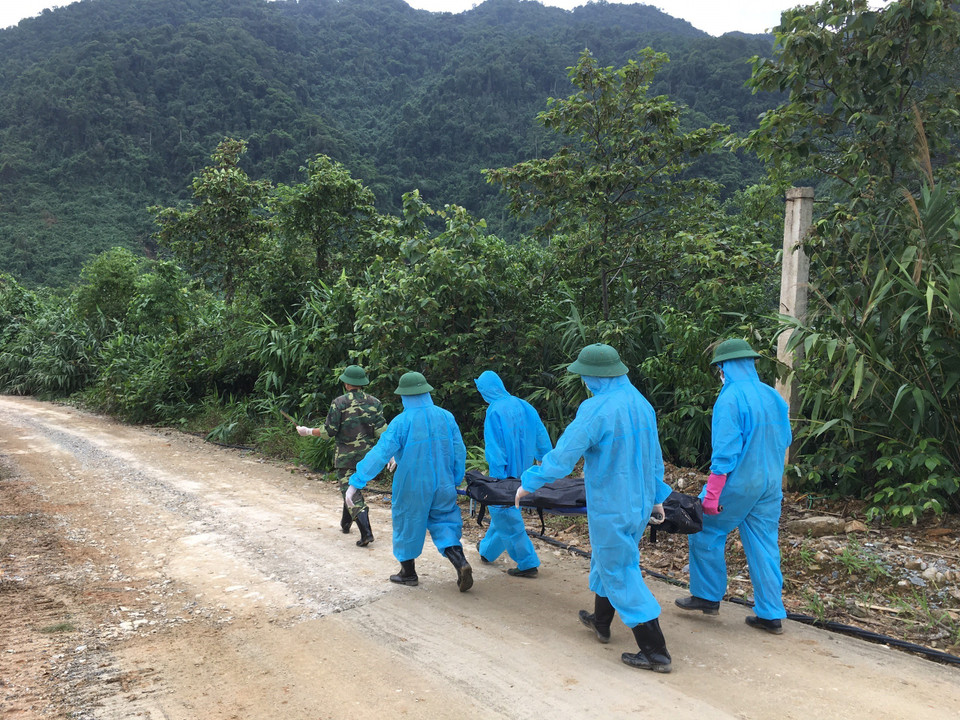 Lực lượng chức năng chuyển nạn nhân ra khỏi khu vực tìm kiếm. (Ảnh: Đỗ Trưởng/TTXVN)