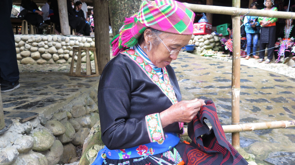 Người dân bản Sin Suối Hồ tranh thủ thêu những tấm thổ cẩm, tạo thành sản phẩm để bán cho du khách. (Ảnh: Việt Hoàng/TTXVN)