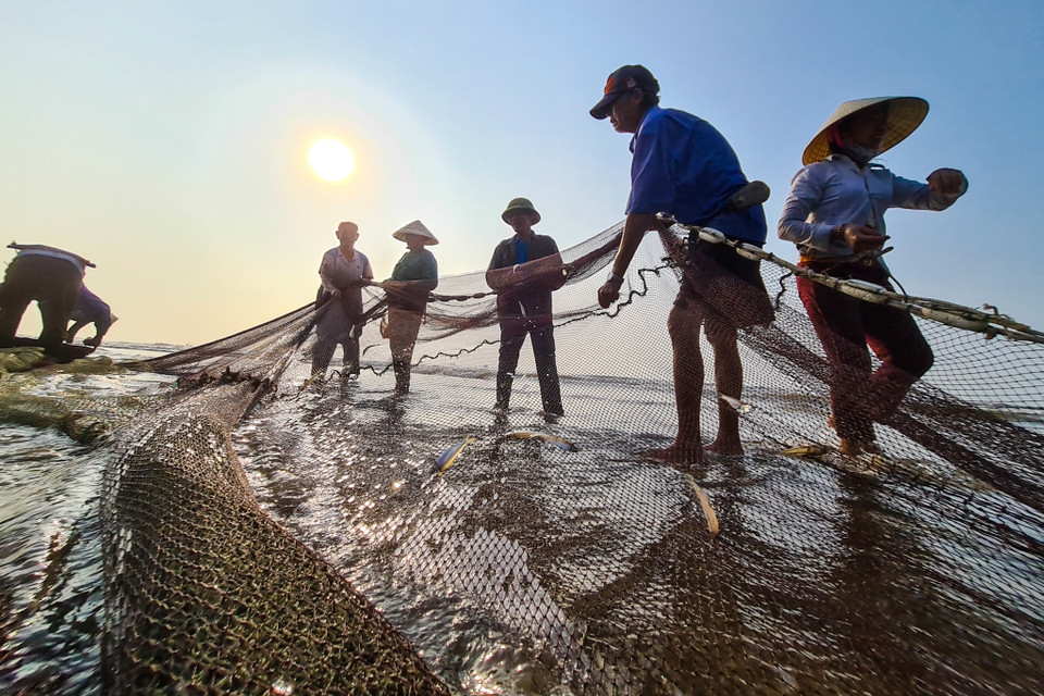 Người dân làng chài gỡ lưới. (Nguồn: Vietnam+)