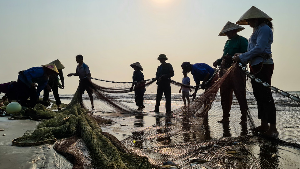 Người dân làng chài gỡ lưới. (Nguồn: Vietnam+)