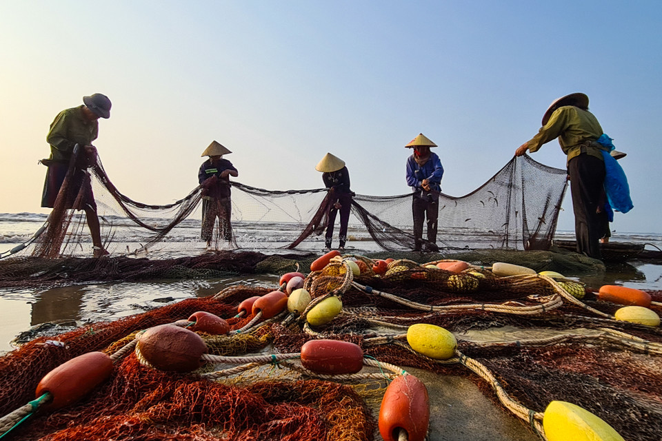 Người dân làng chài gỡ lưới. (Nguồn: Vietnam+)