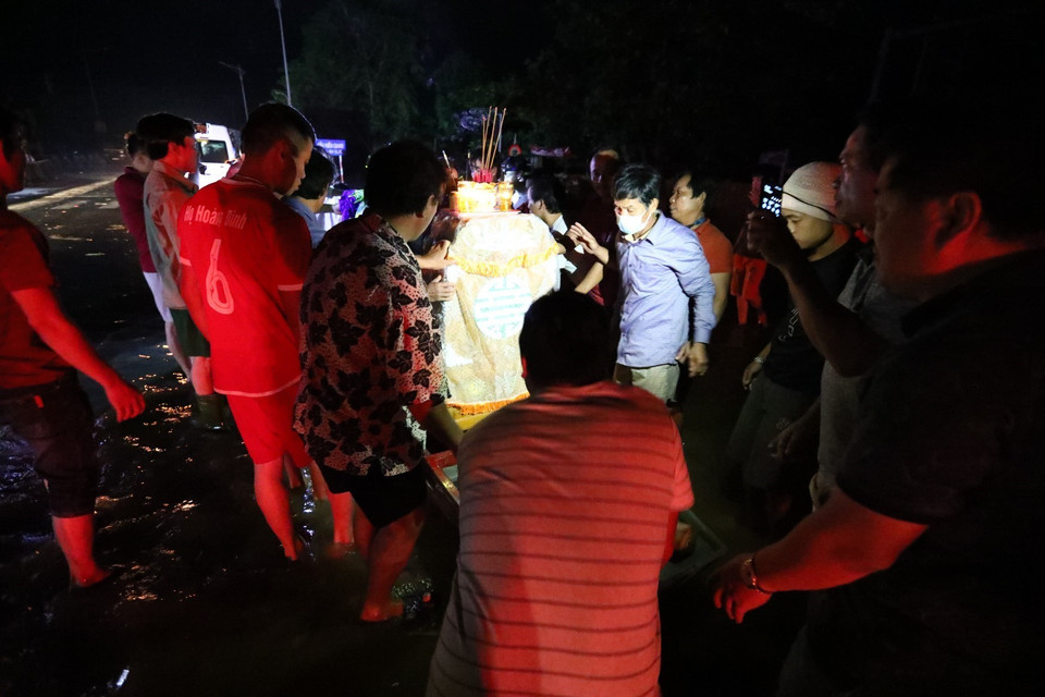 Di chuyển linh cữu lên bè để đưa lên vùng khô ráo cử hành tang lễ. (Ảnh: Thành Đạt/TTXVN)