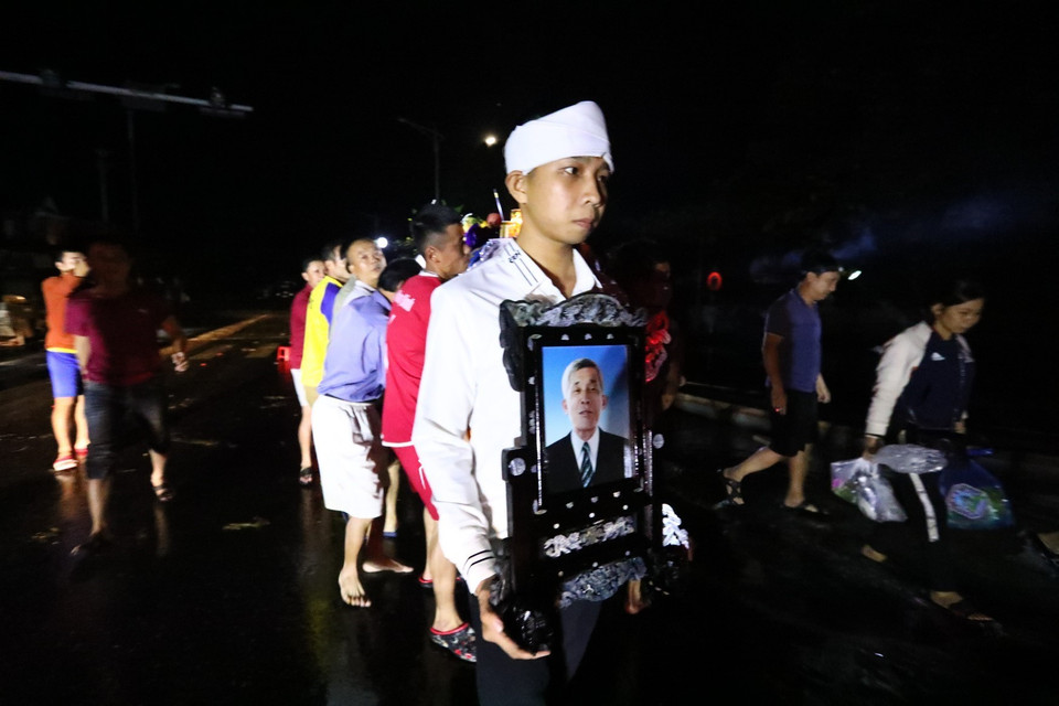 Một gia đình ở thị trấn Kiến Giang, huyện Lệ Thủy, tỉnh Quảng Bình phải di chuyển linh cữu trong đêm. (Ảnh: Thành Đạt/TTXVN)