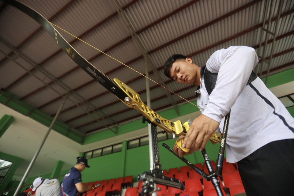 Các vận động viên tập trung "chăm sóc" cây cung của mình trước khi bước vào tập luyện. (Ảnh: Minh Quyết/TTXVN)