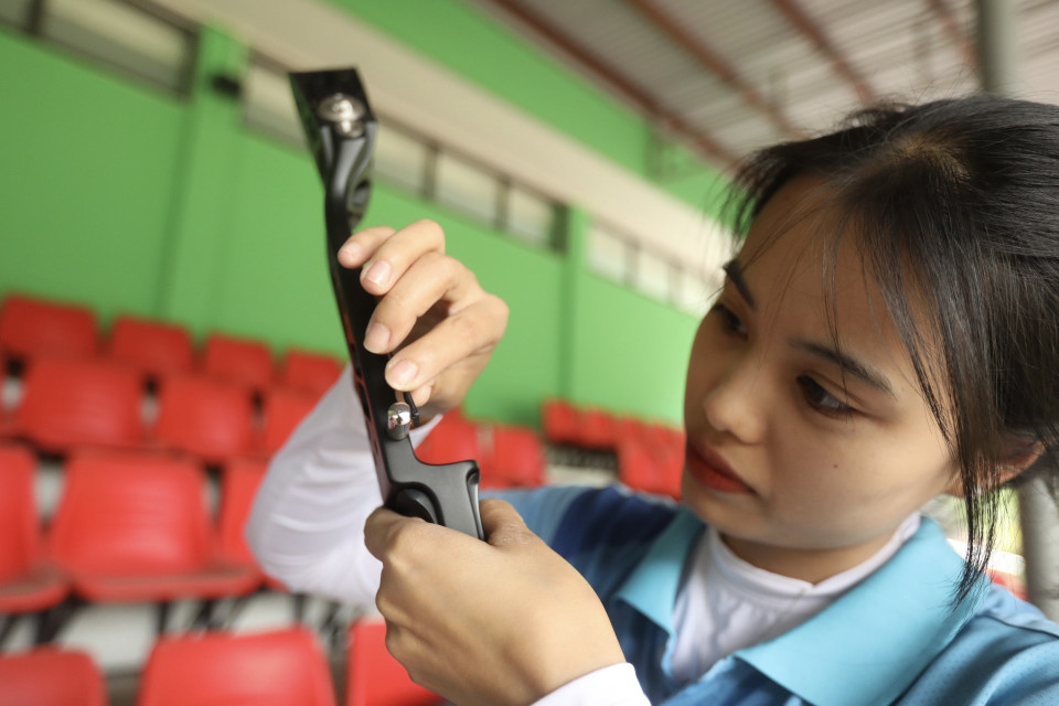 Cung thủ Đỗ Thị Ánh Nguyệt cẩn thận lắp chi tiết cho chiếc cung của mình trước khi bước vào tập luyện. (Ảnh: Minh Quyết/TTXVN)