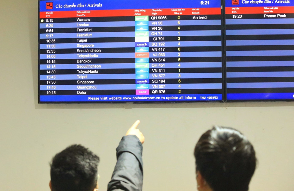 Người thân dõi theo bảng điện tử cập nhật chuyến bay về từ Ba Lan. (Ảnh: Tuấn Anh/TTXVN)