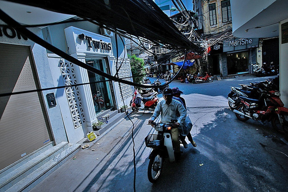 Các loại dây điện, dây viễn thông sà xuống đường ngay phía trên đầu người qua lại khiến ai đi qua cũng phải chú ý né 'tổ nhện' ở ngõ Hội Vũ. (Ảnh: Trọng Đạt/TTXVN)