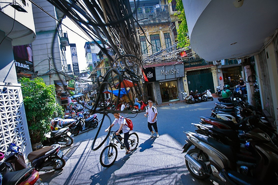 Các loại dây điện, dây viễn thông sà xuống đường ngay phía trên đầu người qua lại khiến ai đi qua cũng phải chú ý né 'tổ nhện' ở ngõ Hội Vũ. (Ảnh: Trọng Đạt/TTXVN)