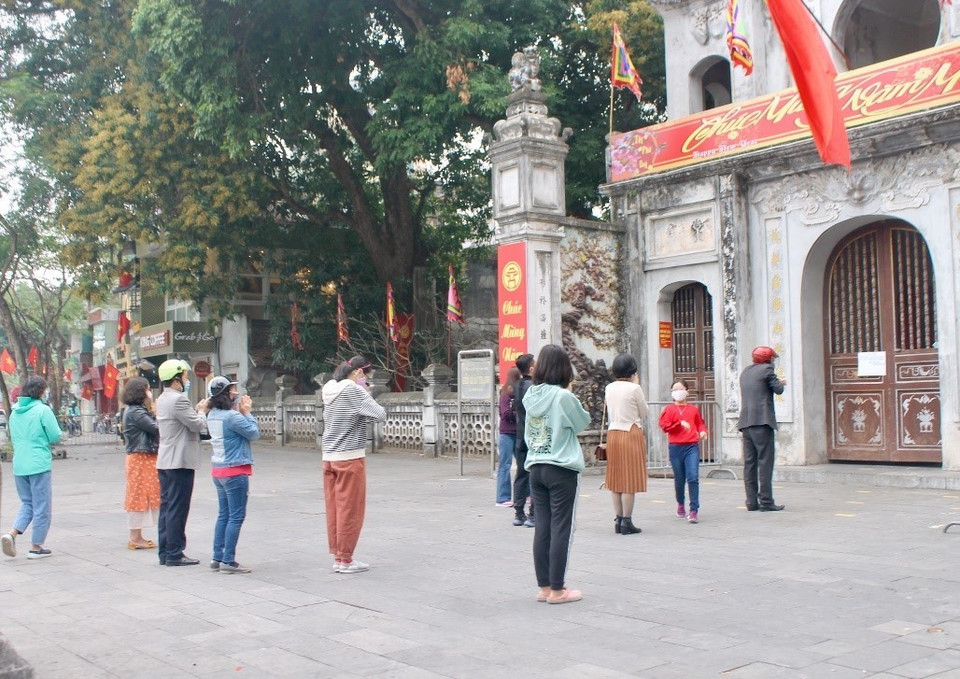 Nhiều người dân đứng lễ ngay trước cửa đền Quán Thánh (quận Tây Hồ, Hà Nội) nhưng đều đeo khẩu trang và đứng có khoảng cách với người bên cạnh. (Ảnh: Minh Nghĩa/TTXVN)