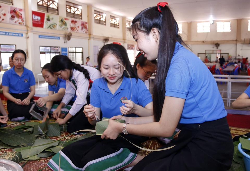 Các học sinh rất thích thú khi lần đầu tiên được tham gia gói bánh chưng. (Ảnh: Phạm Kiên/Vietnam+)