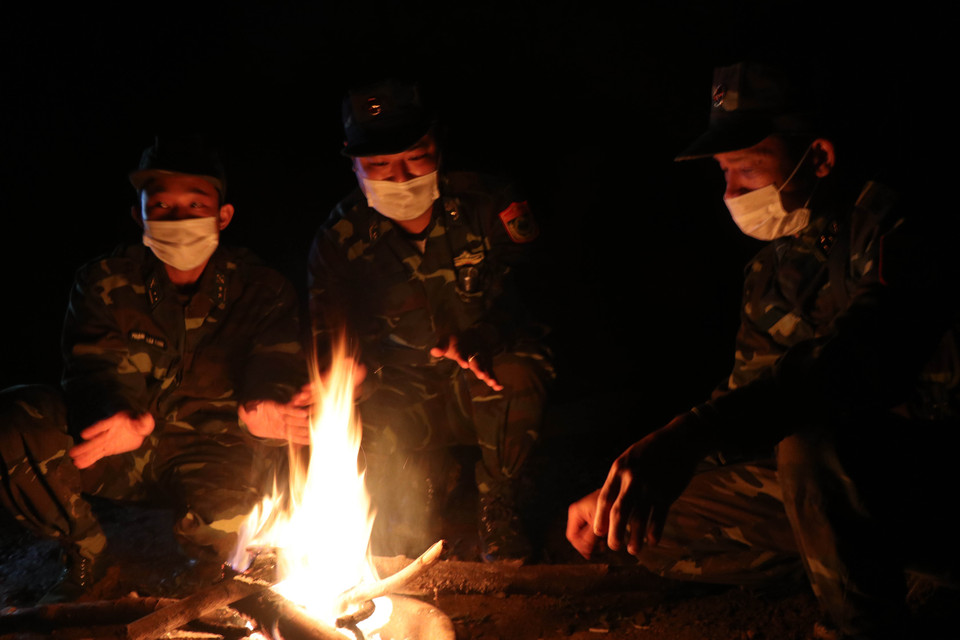 Cán bộ, chiến sỹ Đồn Biên phòng Cửa khẩu A Đớt sưởi ấm bên bếp lửa sau khi đi tuần tra về tại Chốt kiểm soát dịch bệnh COVID-19 số 5. (Ảnh: Đỗ Trưởng/TTXVN)
